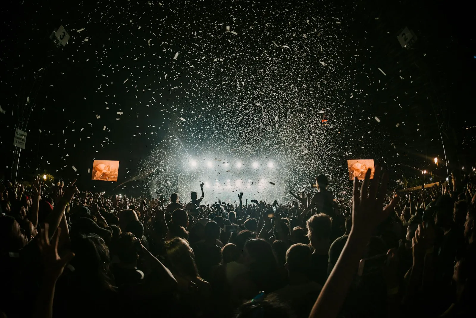 Público de un concierto con confeti frente al escenario iluminado